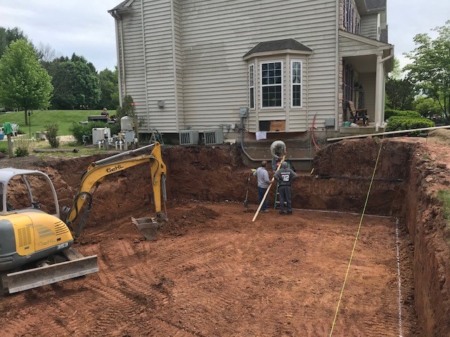 Excavating dirt for a home addition foundation off of the side of a house.