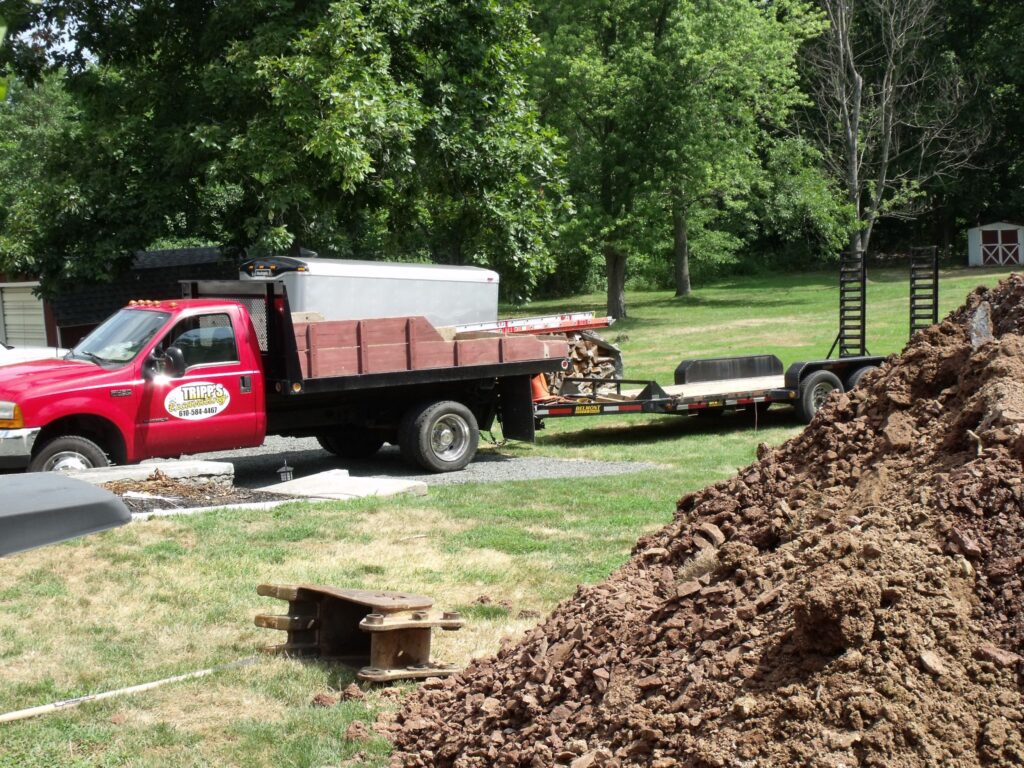 Tripp Excavating and Demoliton services with a dump bed truck and trailer on a job site